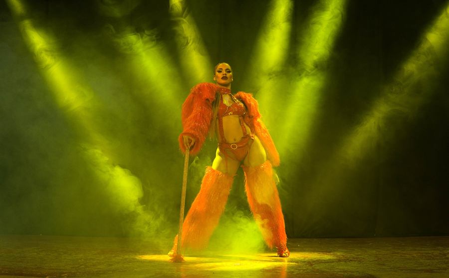 The singer in orange fur, backlit in acid green
