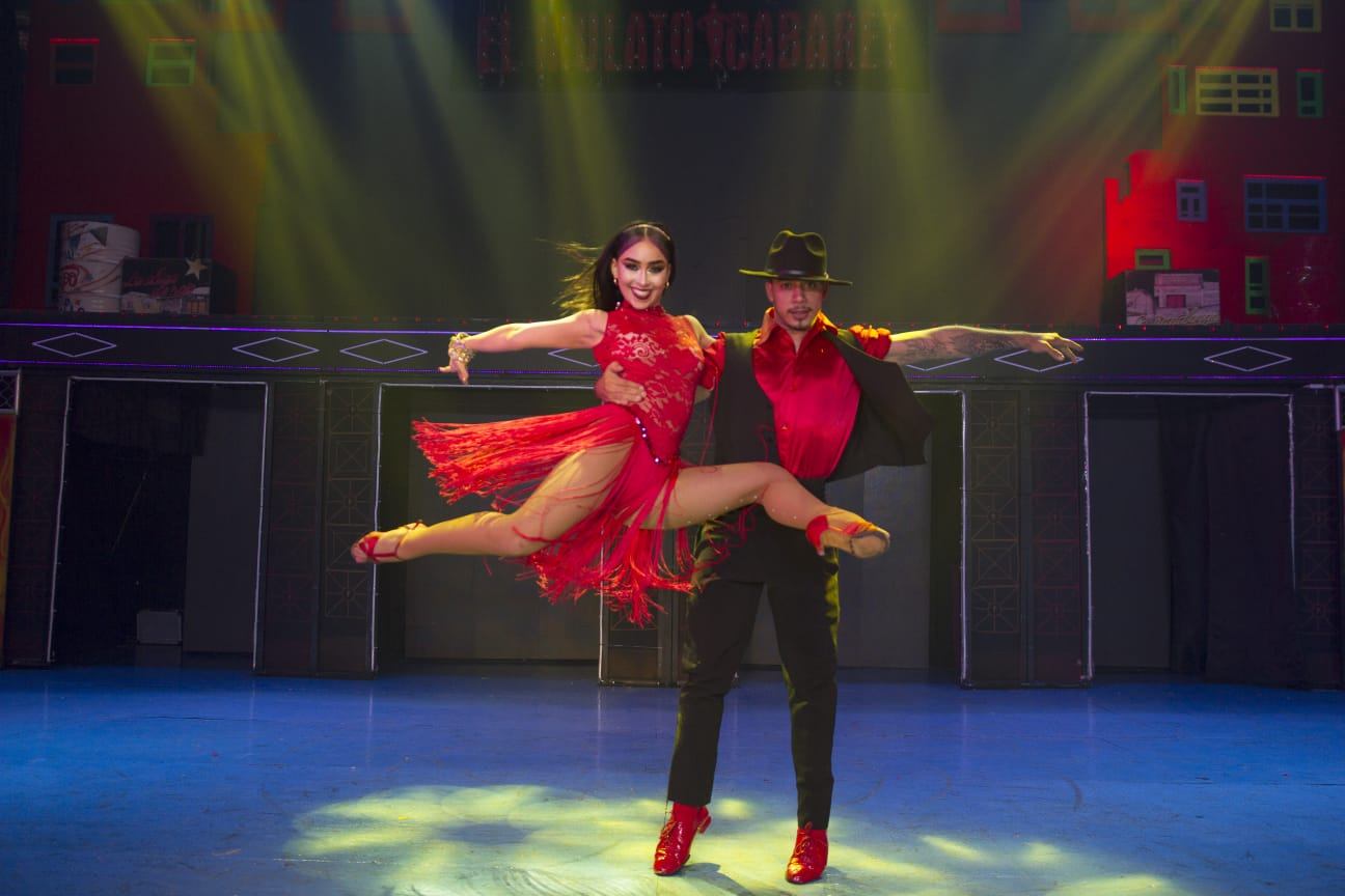 A couple in red caught mid-jump in green stage light